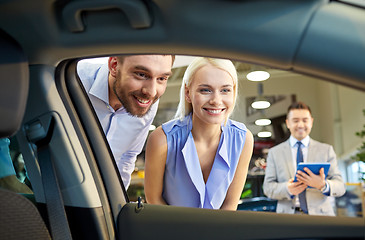 Image showing happy couple with car dealer in auto show or salon