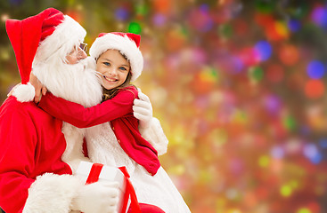 Image showing smiling girl cuddling with santa claus over lights