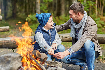 Image showing father and son roasting marshmallow over campfire