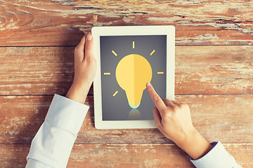 Image showing close up of hands with lighting bulb on tablet pc