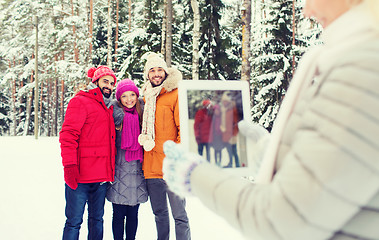 Image showing smiling friends with tablet pc in winter forest