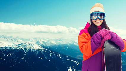 Image showing happy young woman with snowboard over mountains