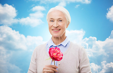 Image showing happy smiling senior woman with flower at home