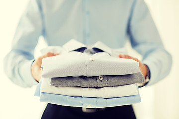 Image showing close up of businessman holding folded shirts