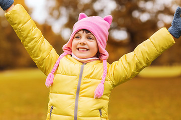 Image showing happy little girl with raised hands outdoors