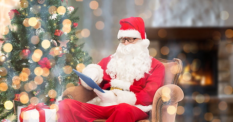 Image showing santa claus with tablet pc in armchair at home