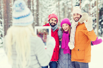 Image showing smiling friends with tablet pc in winter forest