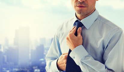 Image showing close up of man in shirt adjusting tie on neck