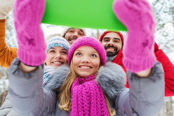 Image showing smiling friends with tablet pc in winter forest