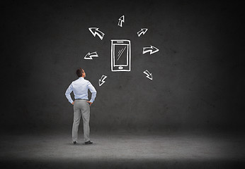 Image showing businessman looking smartphone over concrete wall