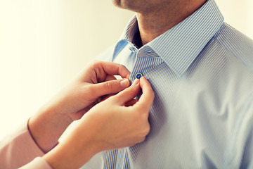 Image showing close up of man and woman fastening shirt buttons