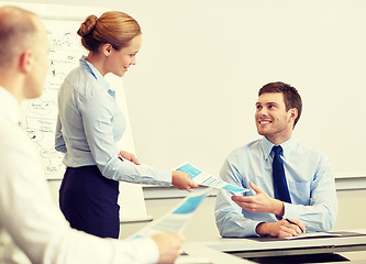 Image showing smiling woman giving papers to man in office