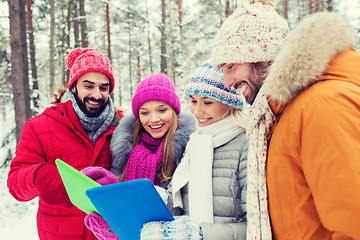 Image showing smiling friends with tablet pc in winter forest