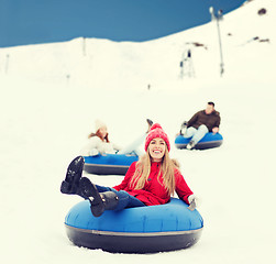 Image showing group of happy friends sliding down on snow tubes