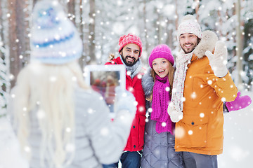 Image showing smiling friends with tablet pc in winter forest