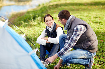 Image showing happy couple setting up tent outdoors