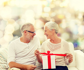 Image showing happy senior couple with gift box at home