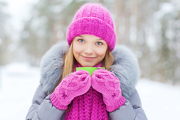 Image showing smiling young woman with cup in winter forest