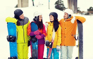 Image showing happy friends in helmets with snowboards talking