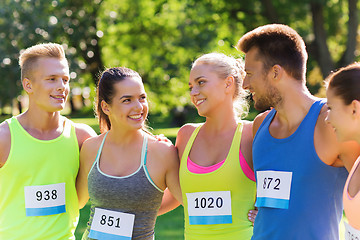 Image showing happy friends or couple with racing badge numbers