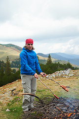 Image showing hiking man prepare tasty sausages on campfire