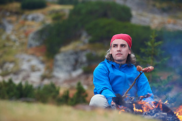 Image showing hiking man prepare tasty sausages on campfire