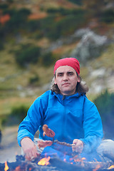 Image showing hiking man prepare tasty sausages on campfire