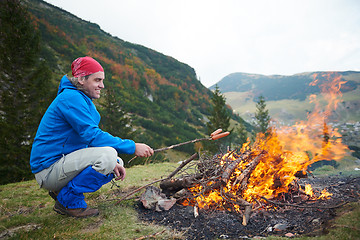 Image showing hiking man prepare tasty sausages on campfire