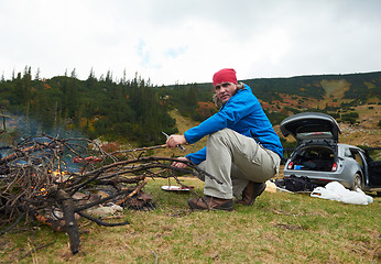 Image showing hiking man prepare tasty sausages on campfire