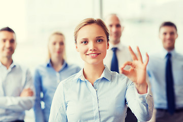 Image showing smiling businesswoman showing ok sign in office