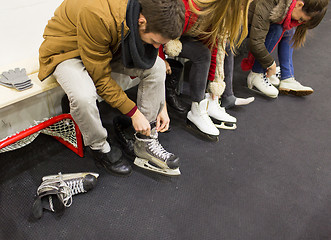 Image showing close up of friends wearing skates on skating rink