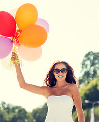 Image showing smiling young woman in sunglasses with balloons