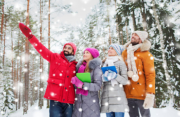 Image showing smiling friends with tablet pc in winter forest