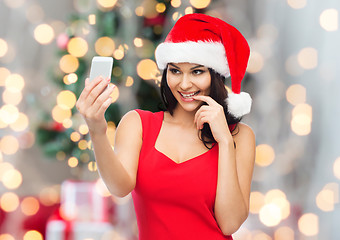 Image showing woman in santa hat taking selfie by smartphone