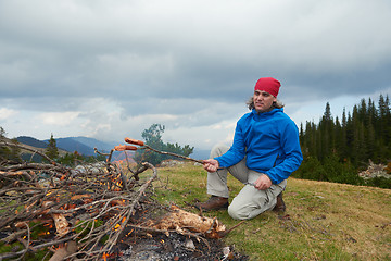 Image showing hiking man prepare tasty sausages on campfire