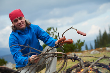 Image showing hiking man prepare tasty sausages on campfire