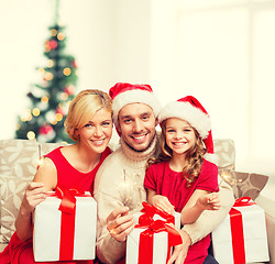 Image showing smiling family holding gift boxes and sparkles