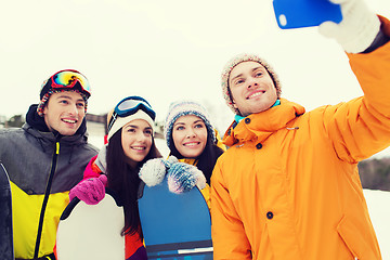 Image showing happy friends with snowboards and smartphone