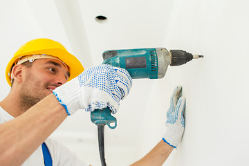 Image showing builder in hardhat with drill perforating wall