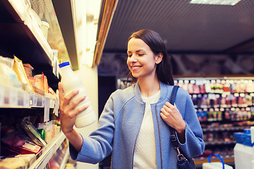 Image showing happy woman holding milk bottle in market