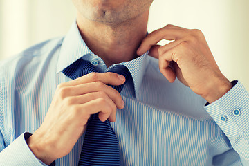 Image showing close up of man in shirt adjusting tie on neck