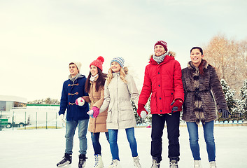 Image showing happy friends ice skating on rink outdoors