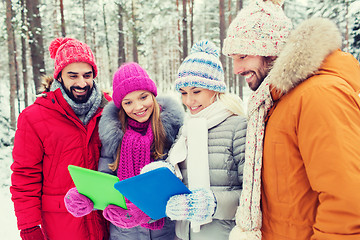 Image showing smiling friends with tablet pc in winter forest