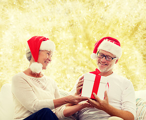 Image showing happy senior couple in santa hats with gift box