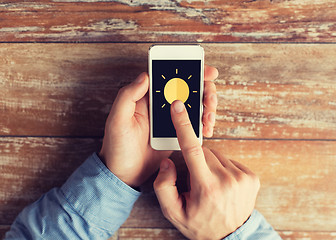 Image showing close up of hands with sun icon on smartphone