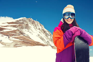 Image showing happy young woman with snowboard over mountains