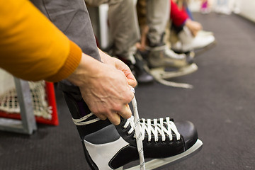 Image showing close up of friends wearing skates on skating rink