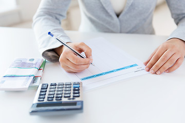 Image showing close up of hands counting money with calculator