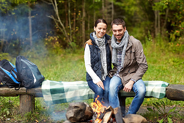 Image showing happy couple sitting on bench near camp fire