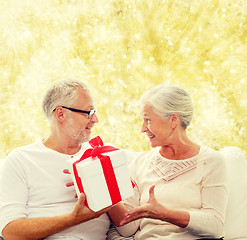 Image showing happy senior couple with gift box at home